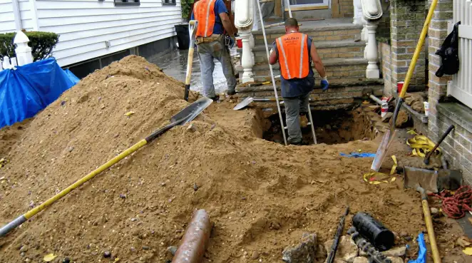 Contractors performing foundation protection and exterior drainage excavation near residential home steps in Tucson, AZ