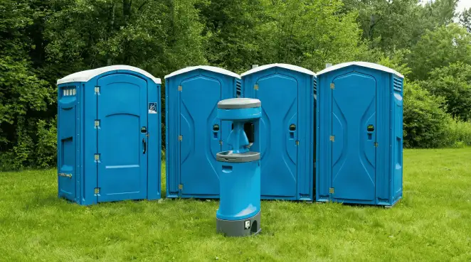 Four blue portable toilets and a matching hand washing station on grass near trees, a common sight at local outdoor events in Tucson, AZ