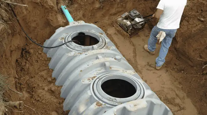 Septic tank installation showing a technician compacting soil around a new poly septic tank in an excavation pit in Tucson, AZ
